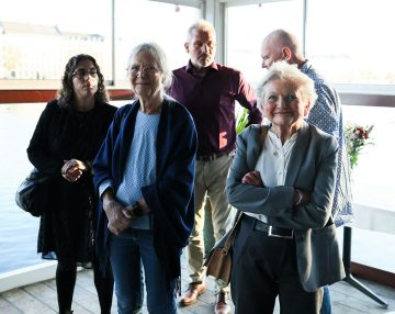 A diverse group of five adults standing together at an indoor event