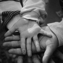 eople stacking their hands together, representing humanity, compassion and mutual support