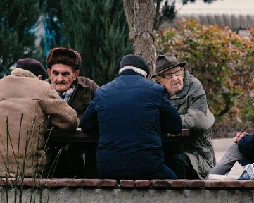 Five elderly men sitting together and talking outdoors